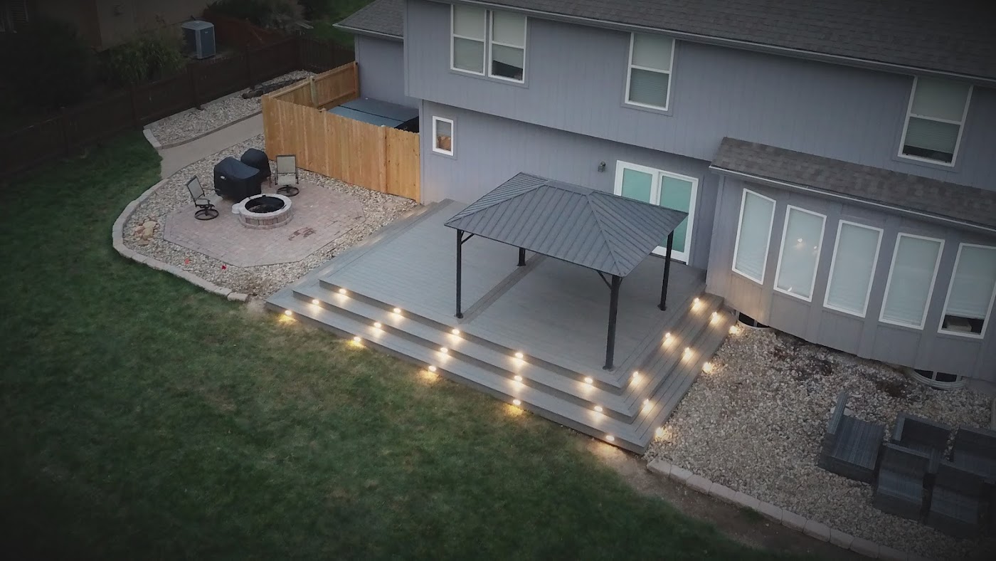 Finished backyard patio with a covered gazebo and deck lighting in the evening