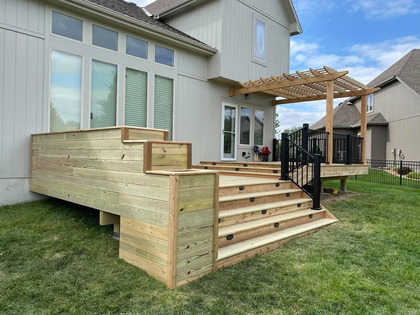 Ground-level pressure-treated deck with wide steps and a pergola